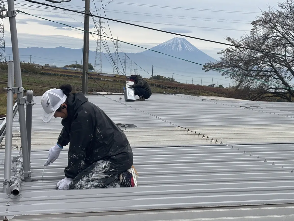 富士山を望む現場で屋根を塗装する職人