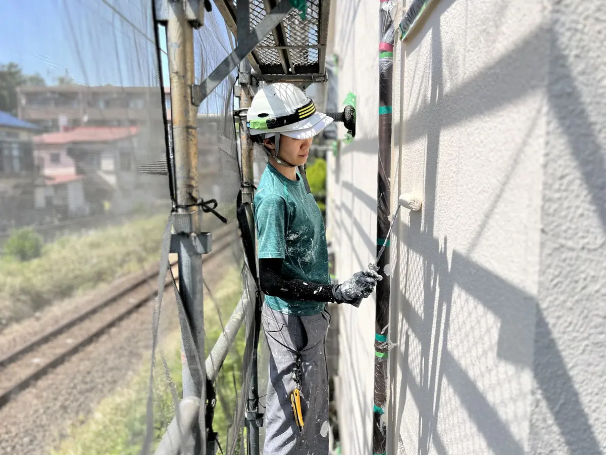 足場の上で外壁を塗装する職人